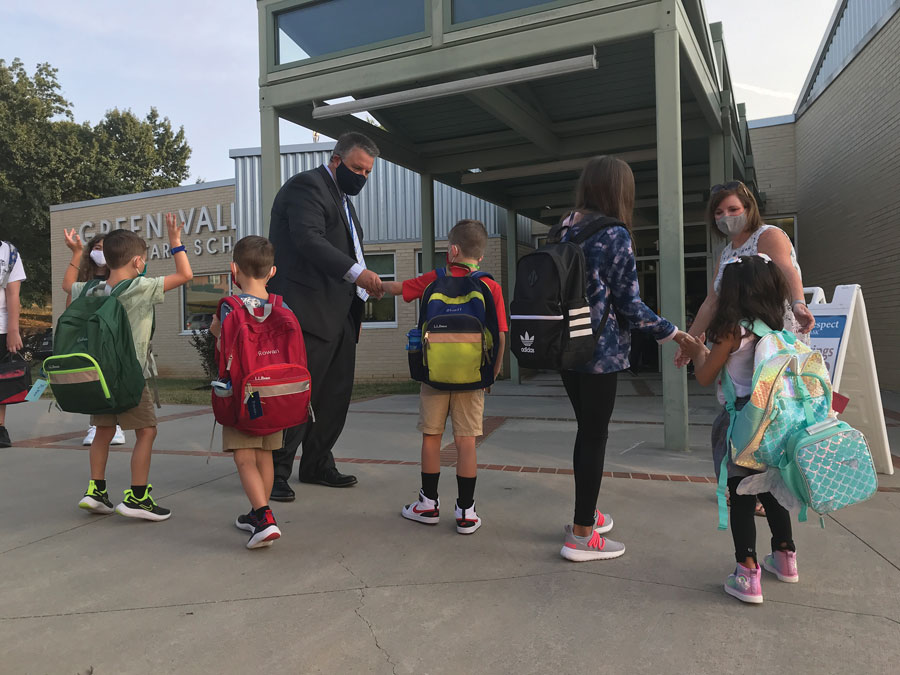 Students celebrate returning to school with their principal and teachers.