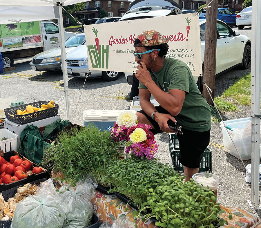 Cam Terry, owner of Garden Variety Harvests, talks with customers at the Grandin Village Farmers Market.