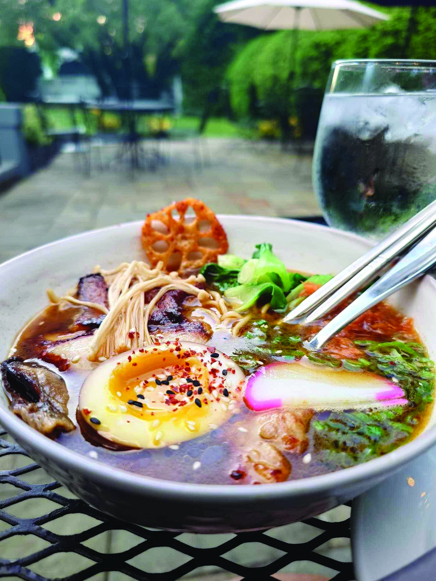 A ramen special garnished with enoki mushrooms, bok choy and a ramen egg.