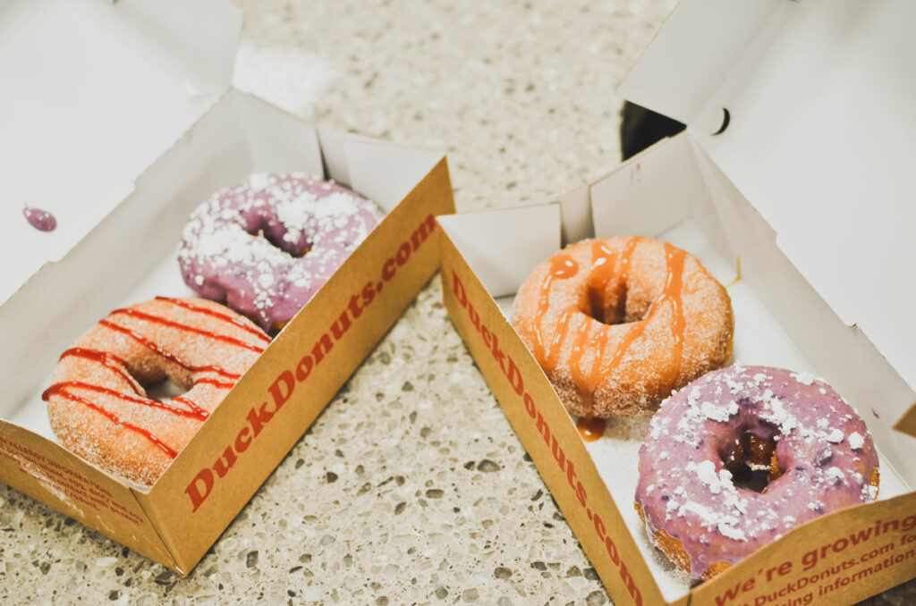 On the left, a cinnamon sugar with raspberry drizzle and a blueberry with powdered sugar; on the right, cinnamon sugar with caramel drizzle and blueberry with powdered sugar.