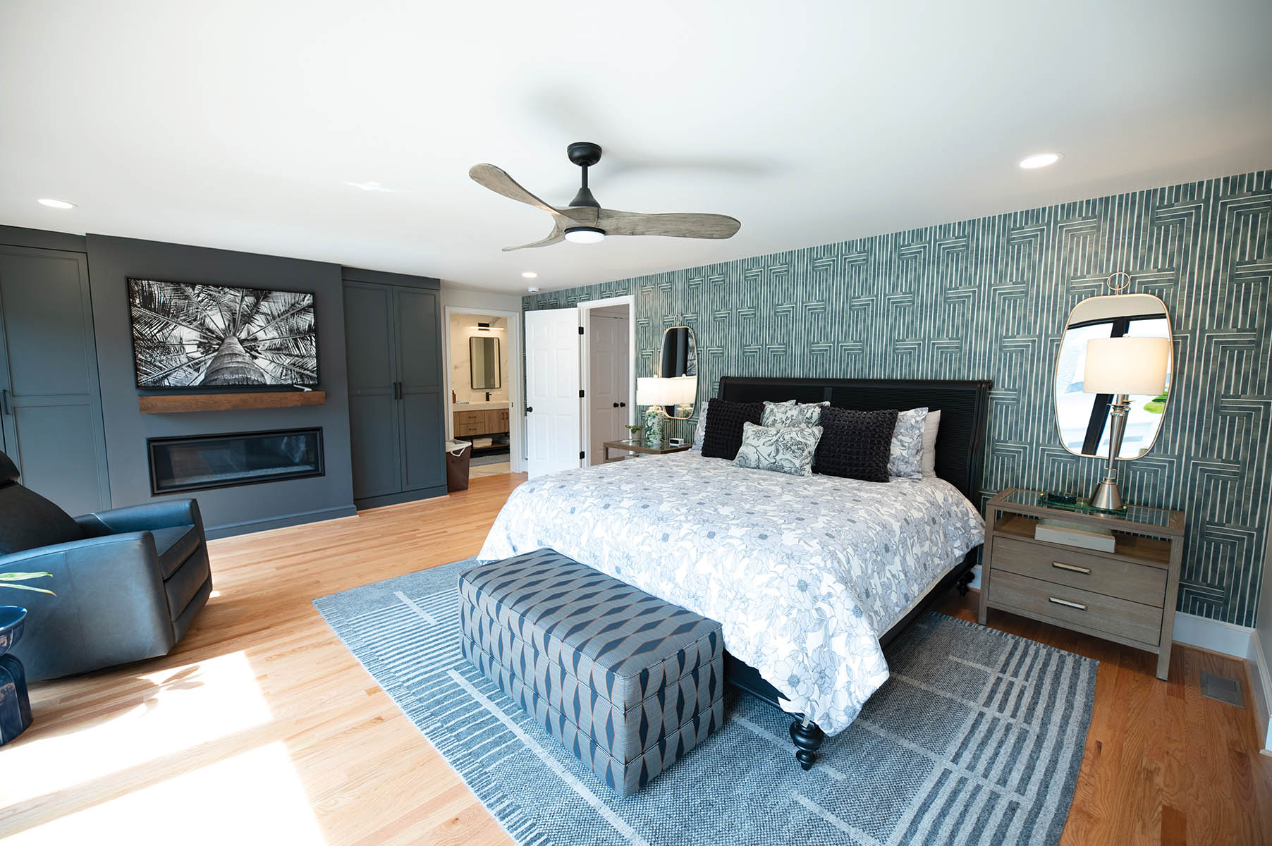 Nicole achieved striking visual interest with her beloved peel-and-stick wallpaper in Chiseled Emerald green, a grey Loloi rug, and a Ted Baker quilt. The geometric patterns in the wallpaper and rug and the floral pattern of the quilt pop in the minimalist space.