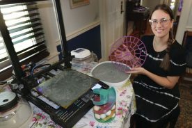 Natalie Ashton with her 3D printer and one of the parts she produces to help incubate chickens.
